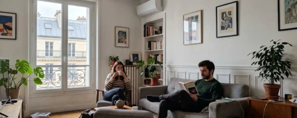 Unité murale de climatisation élégamment intégrée au mur d'un salon contemporain avec lumière naturelle abondante et télécommande posée sur une table basse